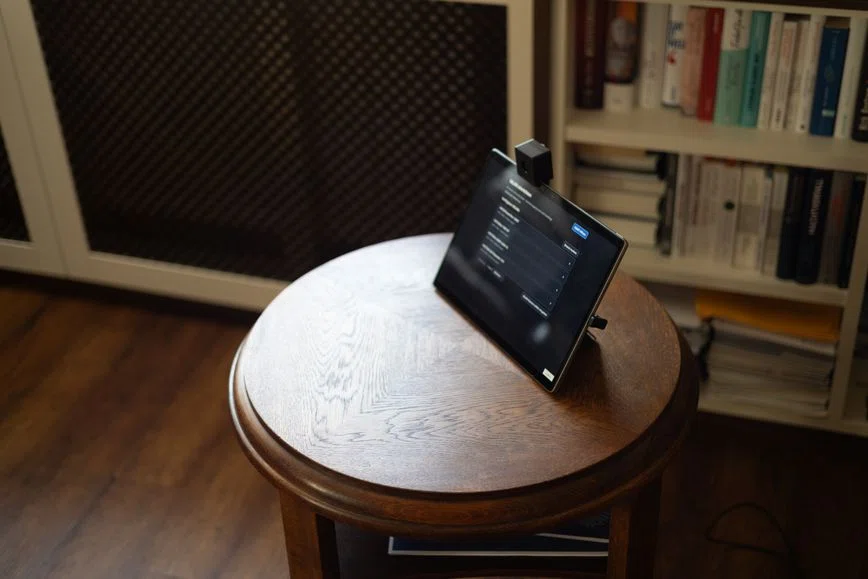 AvatarMediKi-Tablet mit aufgesetzter Kamera auf einem Holztisch; auf dem Display ist eine technische Listenansicht geöffnet.